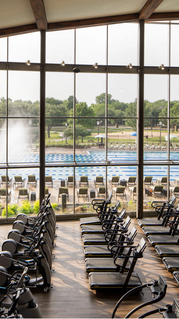 Fitness floor at Life Time McKinney at Craig Ranch looking out at the outdoor pool