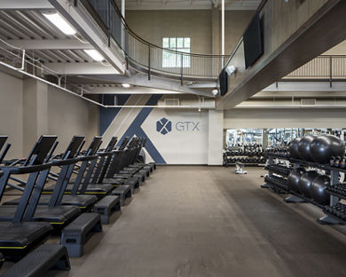 A row of treadmills, kettlebells, and medicine balls in a GTX training area