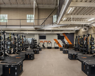 An Alpha training area with plyometric boxes, squat racks, and treadmills