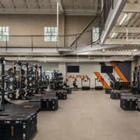 An Alpha training area with plyometric boxes, squat racks, and treadmills