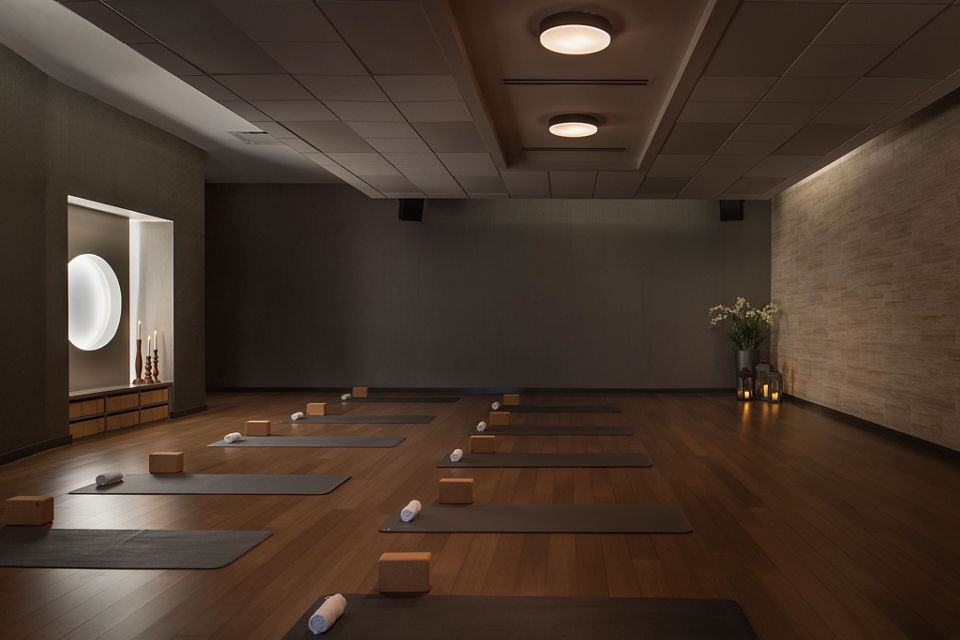 a low lit yoga room with rows of yoga mats