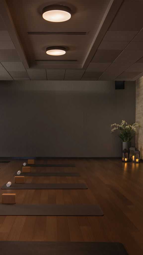 a low lit yoga room with rows of yoga mats