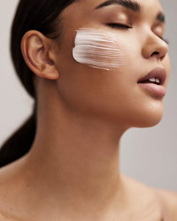 Closeup portrait of an attractive female's face with a brush of lotion across her cheek