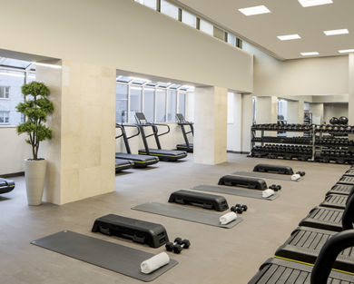 Treadmills, dumbbells and yoga mats laid out in a workout area