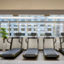 Row of treadmills facing windows leading out to an urban setting