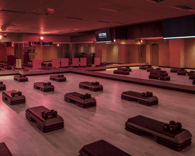 a Life Time Group Fitness Studio with mirrors, aerobic step blocks, and dumbbells