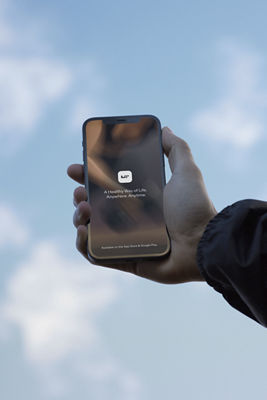 A hand holding a phone with a blue sky in the background