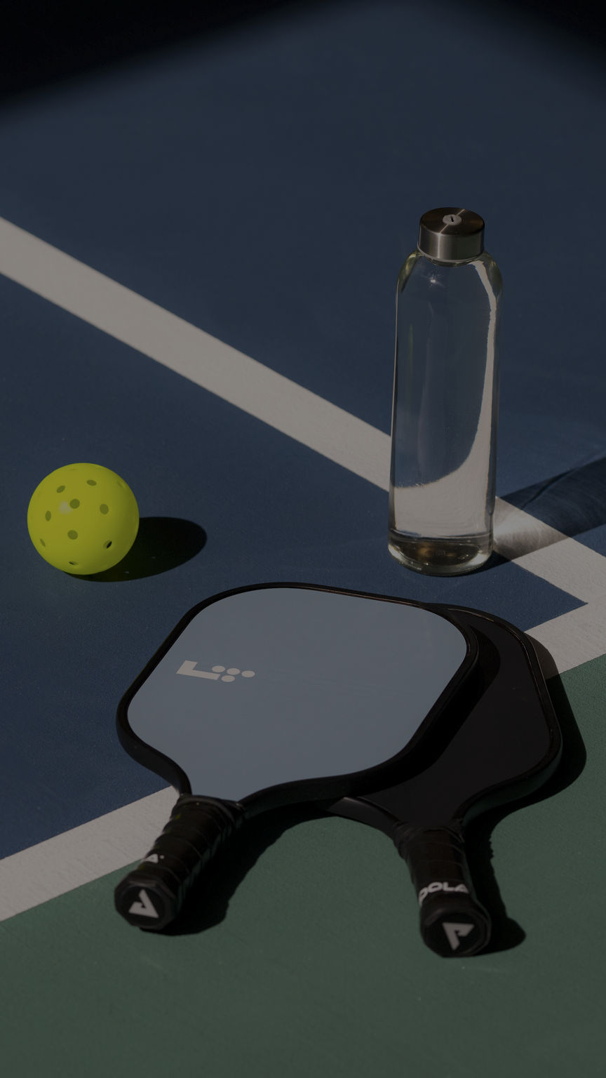 a pickleball, paddle and water bottle sitting on a pickleball court