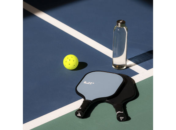 A water bottle and Pickleball paddles laying on an indoor Pickleball court at the Life Time Penn 1 club location