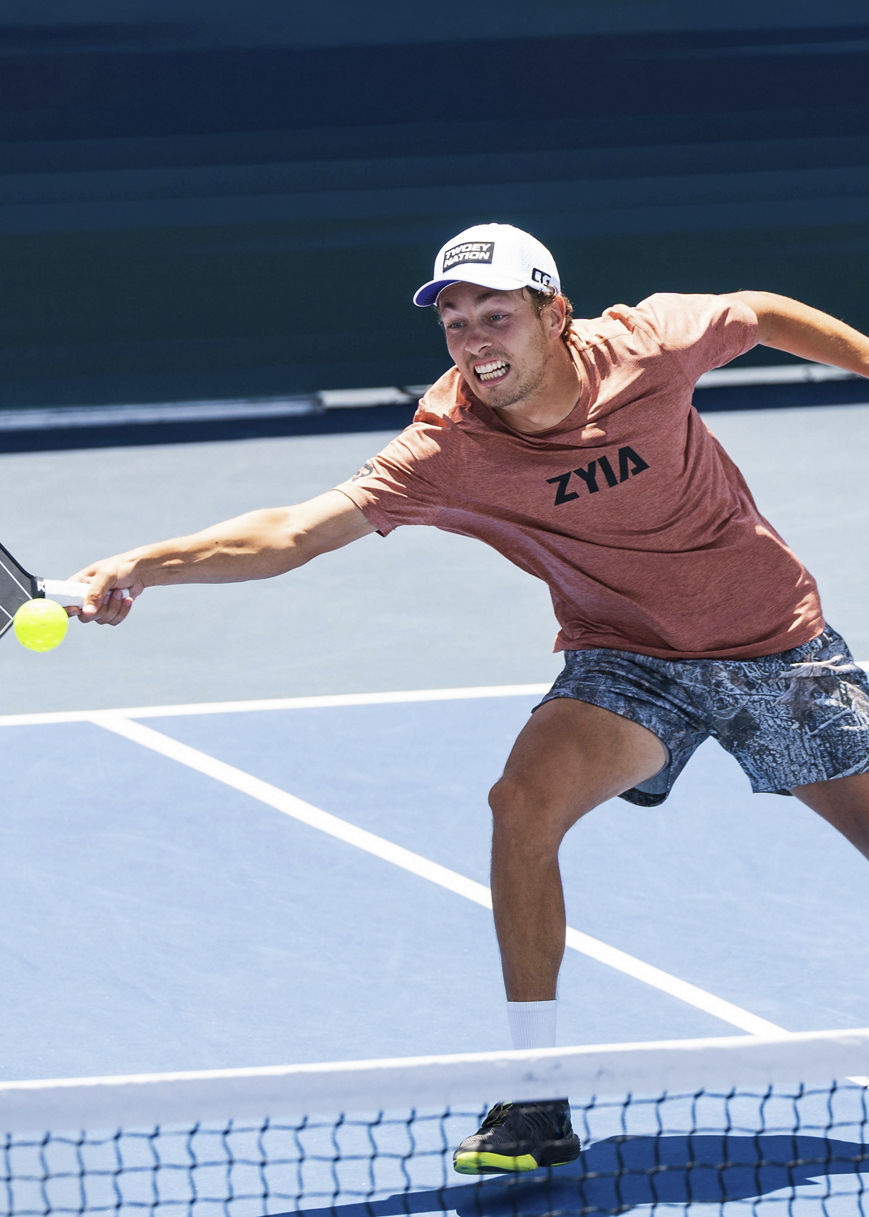 man reahing out with his right arm to hit a pickleball