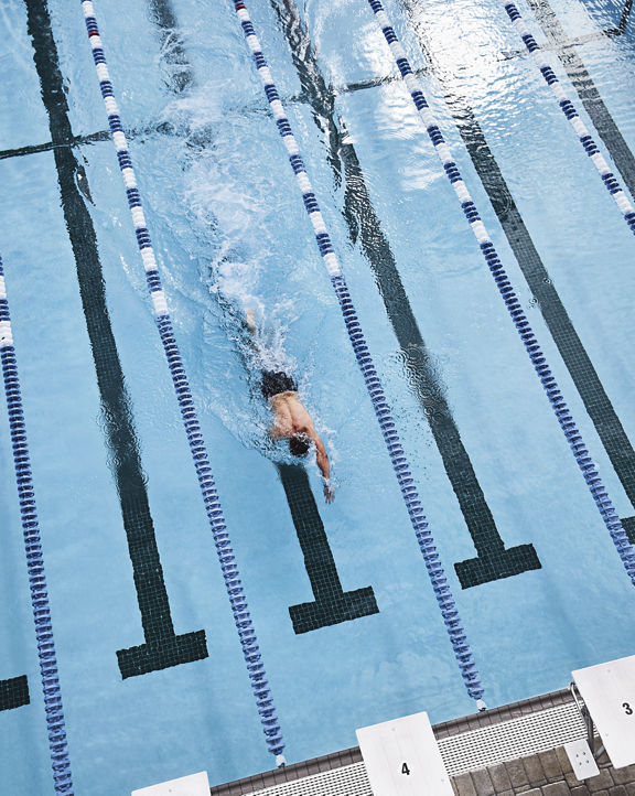 Aerial view of a man swimming laps in an outdoor pool at Life Time