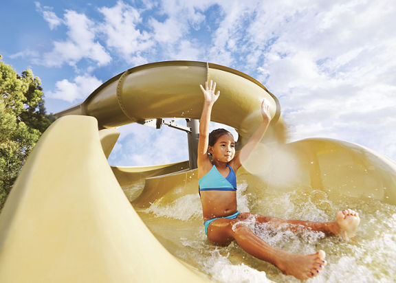 Young girl sliding down a waterslide with sunrays shining on her face