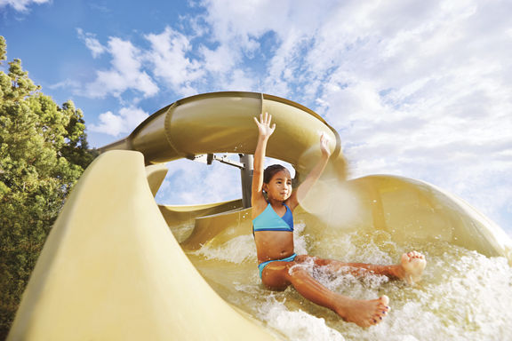 Young girl sliding down a waterslide with sunrays shining on her face