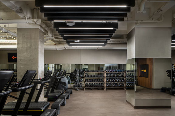 Fitness floor filled with treadmills, dumbbells and kettlebells on racks