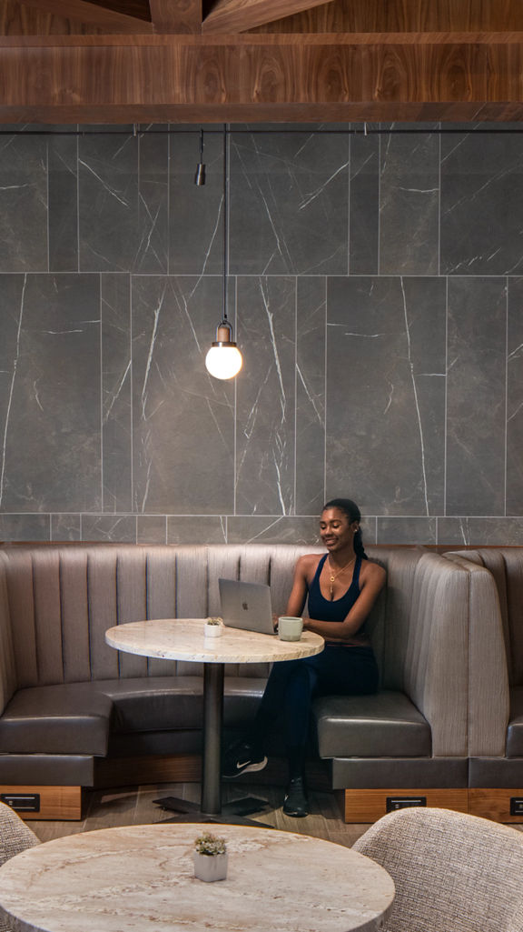 a woman sits at a booth and works on a laptop