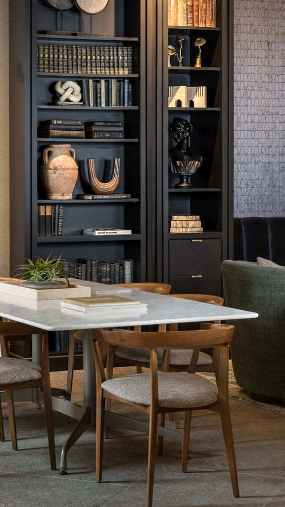 Table and chairs next to a large bookcase and golden wall art