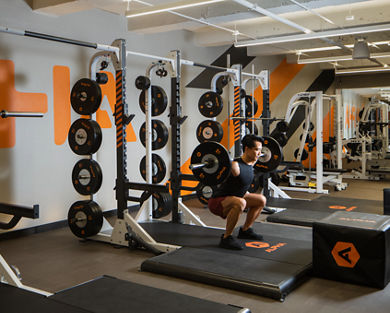 A man completing a squat with heavy weights on his back in an Alpha studio
