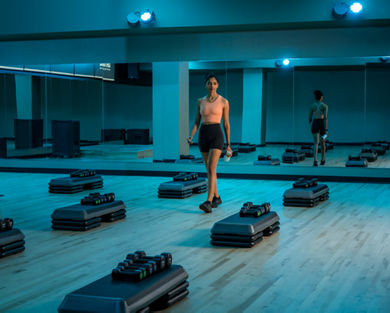 A woman in athletic wear walking through an empty group fitness studio