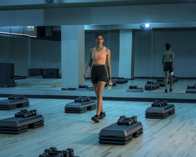 A woman in athletic wear walking through an empty group fitness studio