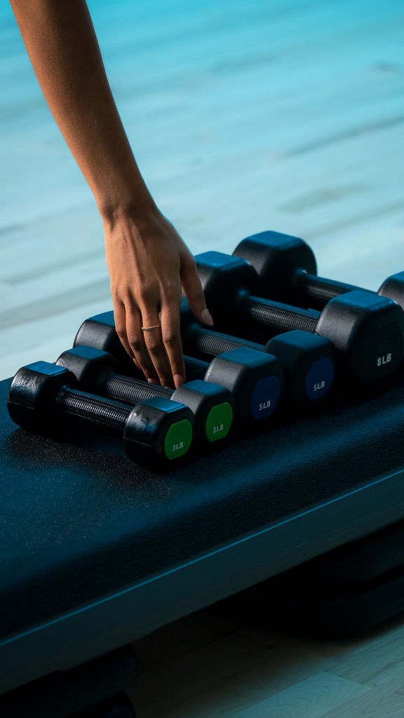 A woman's hand reaches for a dumbbell