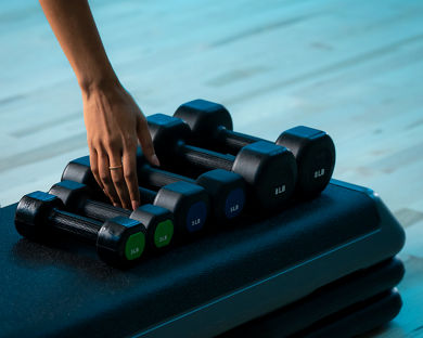 A woman's hand reaches for a dumbbell