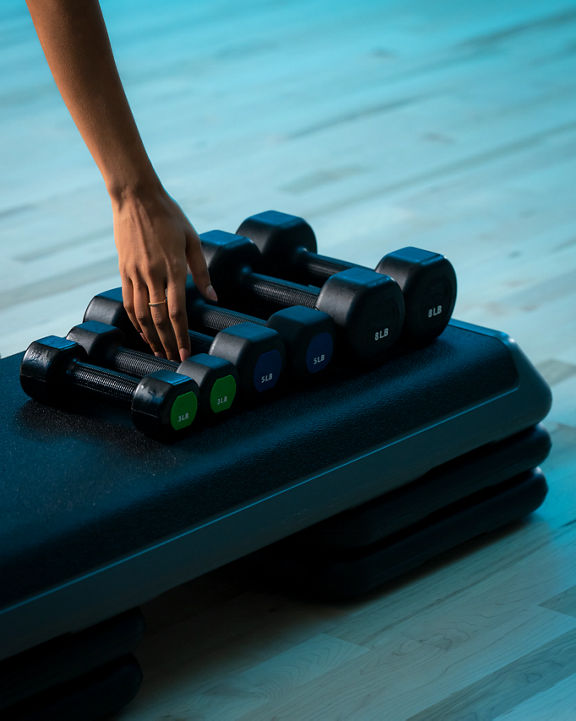 A woman's hand reaches for a dumbbell