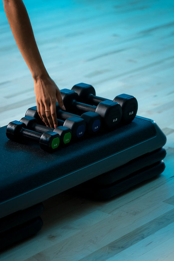 A woman's hand reaches for a dumbbell