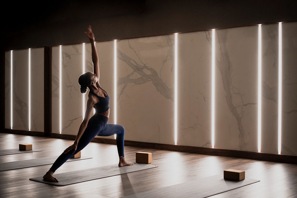 A female completing a reverse warrior pose on a mat in a yoga studio