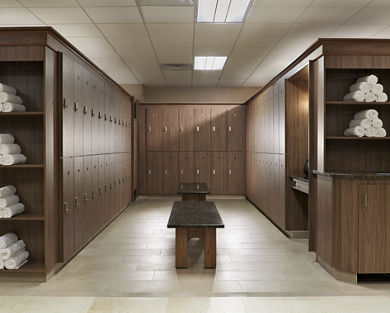 Wooden locker room bay with marble benches and rolled up towels
