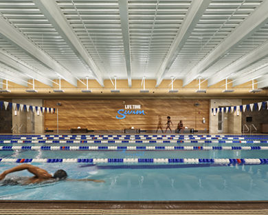 An adult male swimming laps in an indoor lap pool