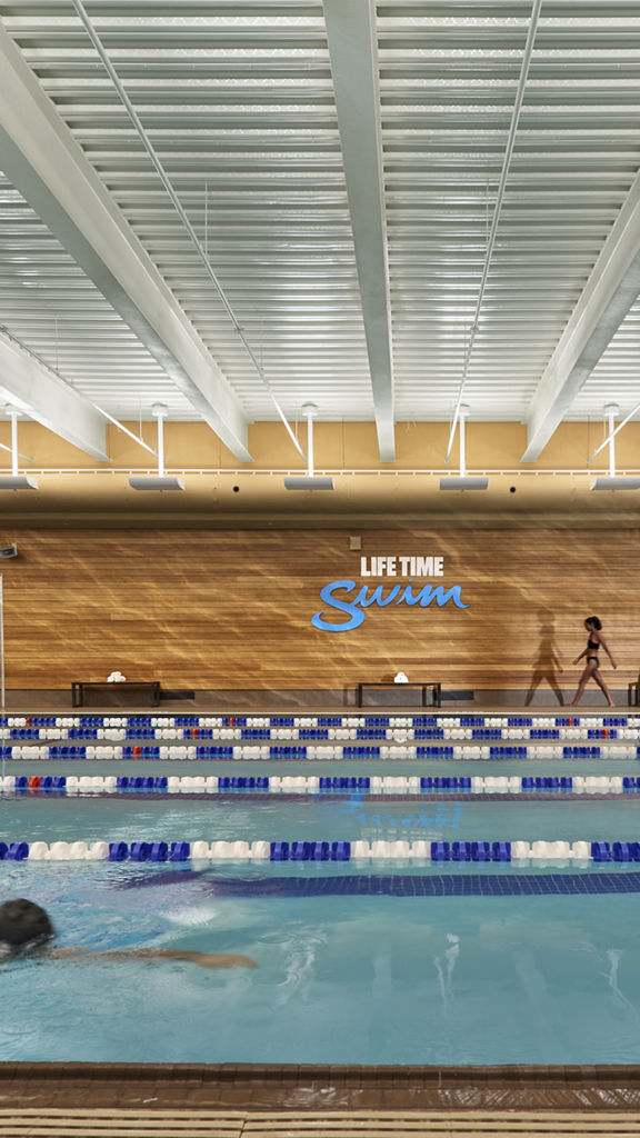 An adult male swimming laps in an indoor lap pool