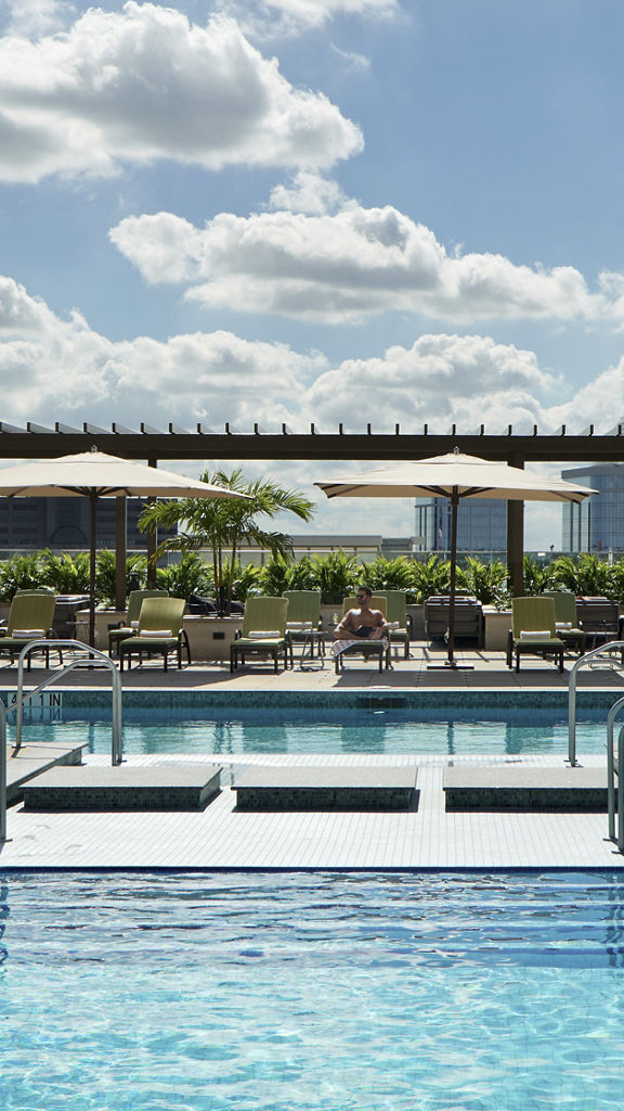 2 people enjoy a sparkeling outdoor pool and deck area with lounge chairs