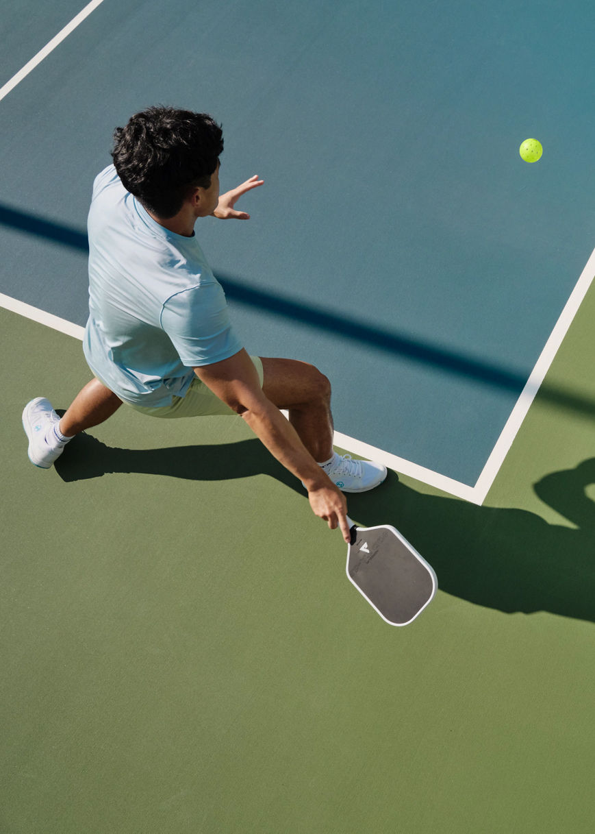 Closeup of a pickleball player on an outdoor court about to hit the ball