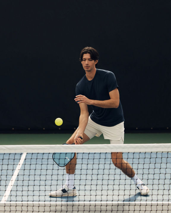 A pickleball player dinking over the net during a game at Life Time