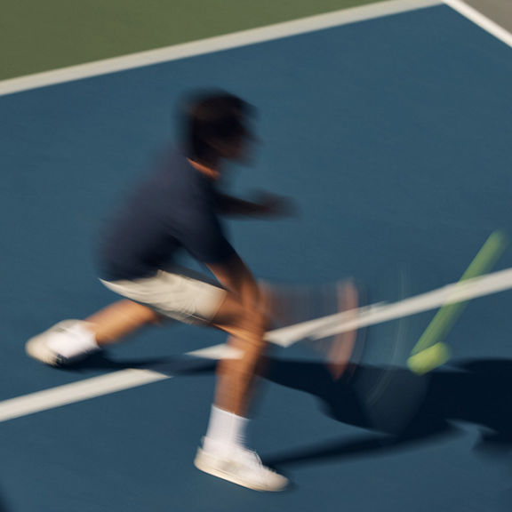 Stylized blurred image of a pickball player swinging at a pickleball