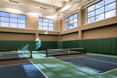 two indoor picklebal courts set for a match in a sunny environment.