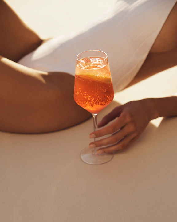 Closeup of a young adult woman wearing a bathing suit while lounging poolside with a drink