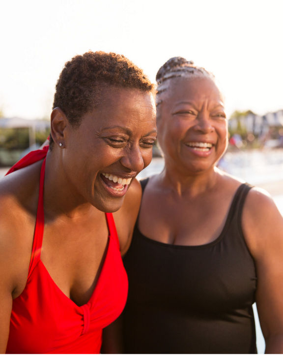 Two women wearing bathing suits standing next to an outdoor pool at Life Time