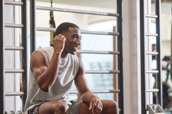 Portrait of an adult male sitting on the edge of an Outrace training device putting in ear buds