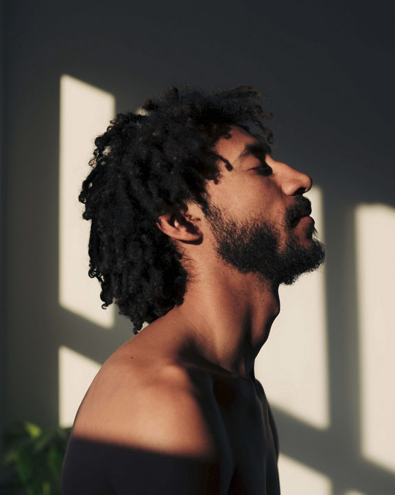Side view portrait of an attractive multiracial man with a beard, lighted by the sunbeam.