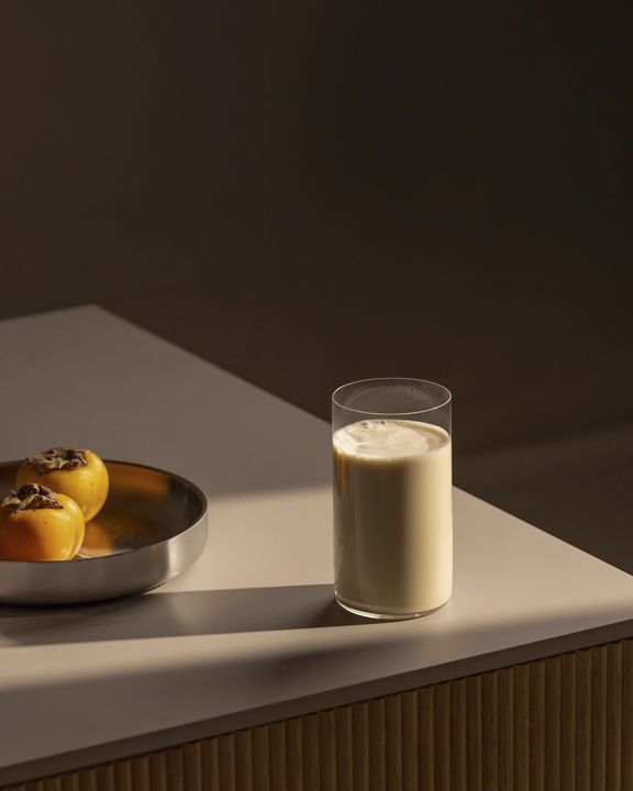 protien glass sitting on a counter with a bowl of fruit
