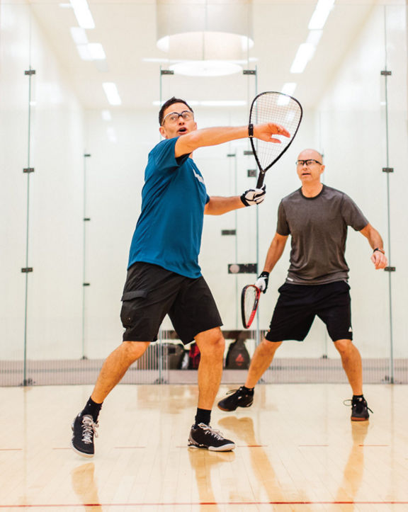 Two men playing racquetball on a racquetball court at Life Time