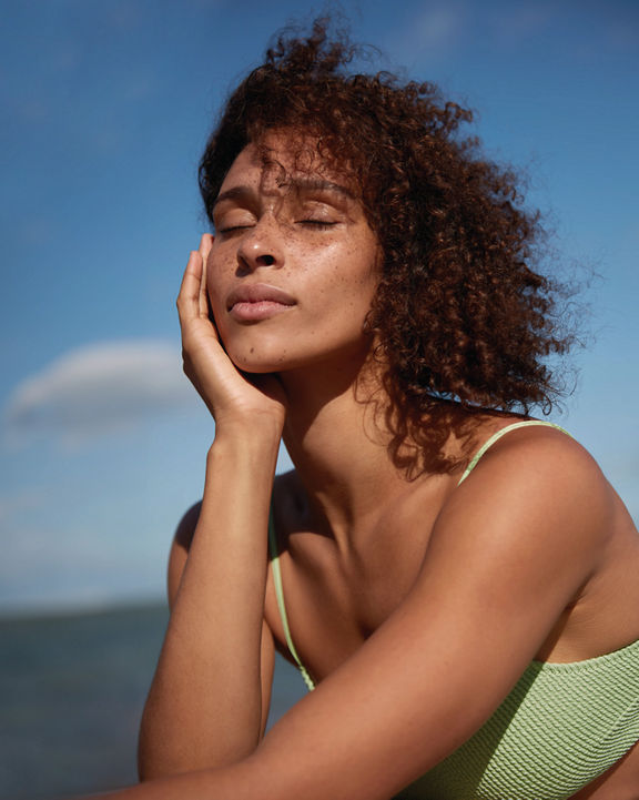 Closeup portrait of a female in a bathing suit enjoying the sun and breeze on her face