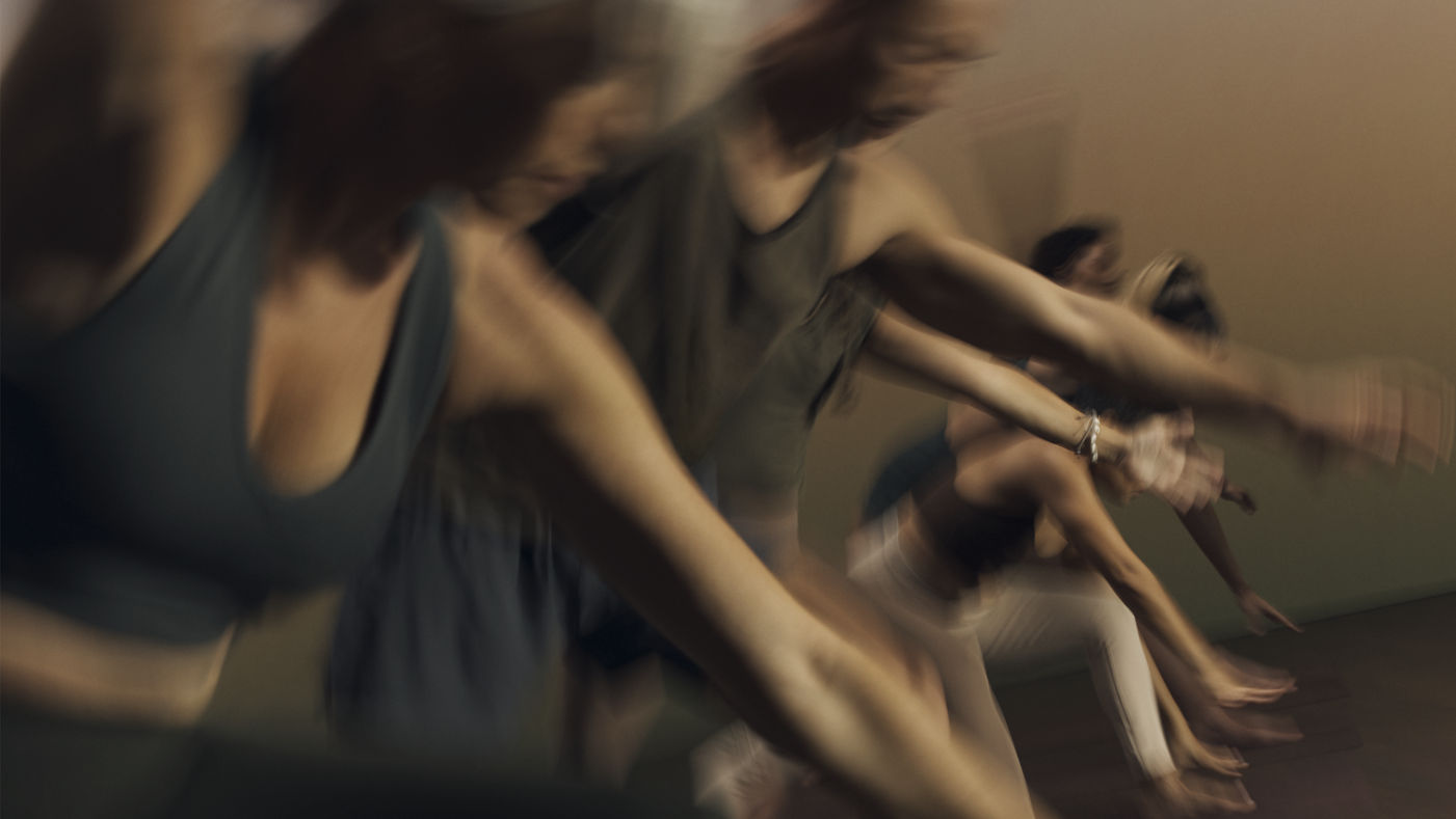 Stylized blurred image of Root yoga class participants moving through a pose at Life Time