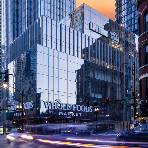 The glass exterior and busy street of Life Time River North at One Chicago at dusk