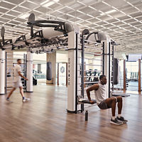 A man doing tricep dips on the edge of an outrace on an open fitness floor