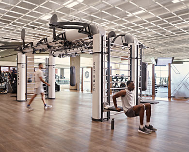 A man doing tricep dips on the edge of an outrace on an open fitness floor