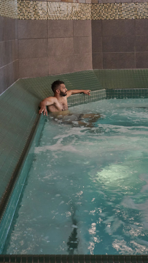 A man sitting and relaxing in an indoor whirlpool at the Life Time South Austin club location