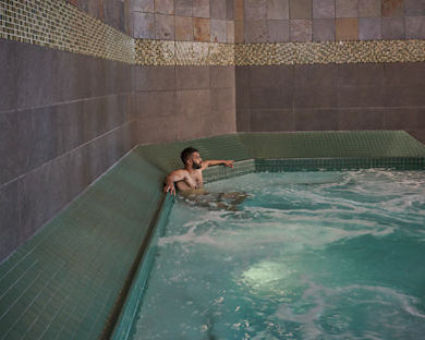 A man sitting and relaxing in an indoor whirlpool at the Life Time South Austin club location