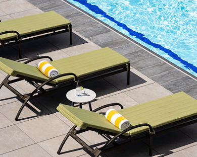 Lounge chairs uniformly positioned poolside at a Life Time outdoor pool